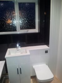 modern sink unit in black tiled bathroom